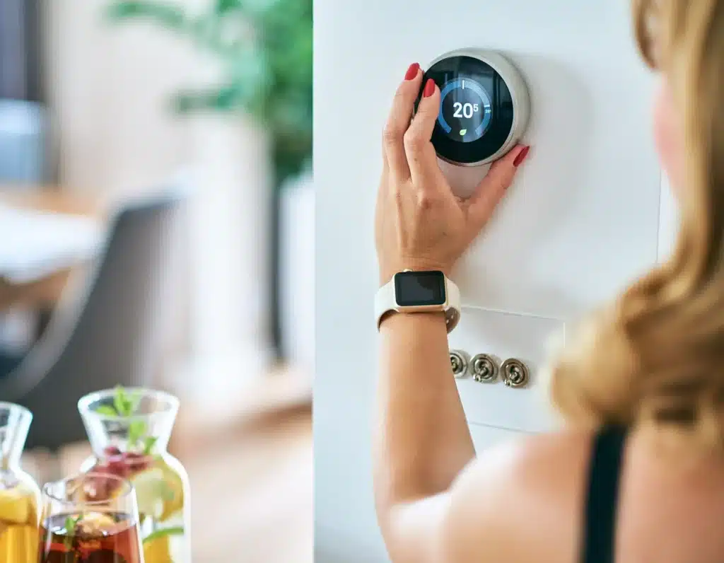 Woman adjusting temperature on smart thermostat.