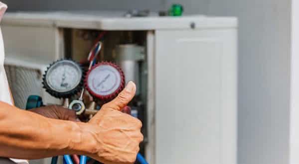 Two hands holding a boiler checking device and reading the controls.