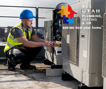 Man wearing a safety vest and a hard hat working on a HVAC system.