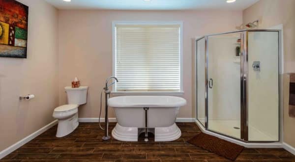 Peach colored bathroom with a toilet, bathtub, and shower.