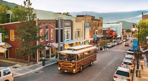 City bus driving through town on a main street.