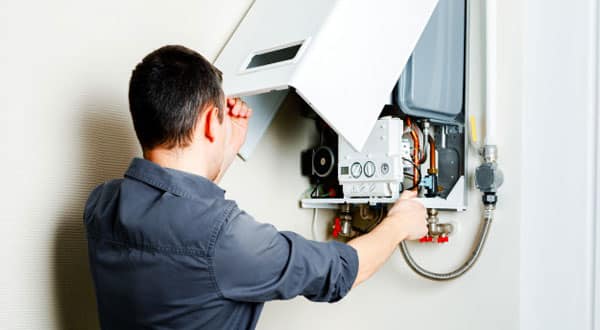 A man lifting a lid of a heater on the wall.